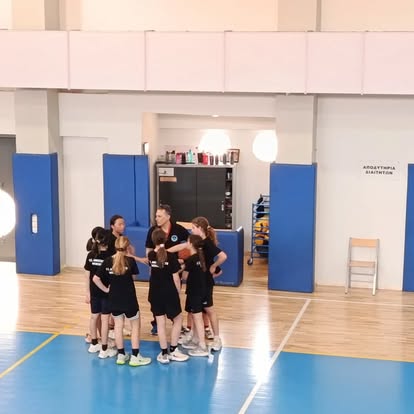 Νεαρές αθλήτριες συζητούν με τον προπονητή στο παρκέ